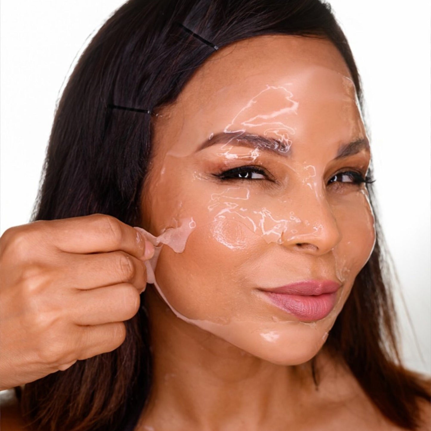A woman peeling off the CO2Lift Pro carboxytherapy gel mask treatment from her face