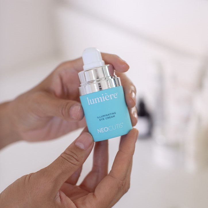 Hands holding the Neocutis Lumiere Firm Eye Cream