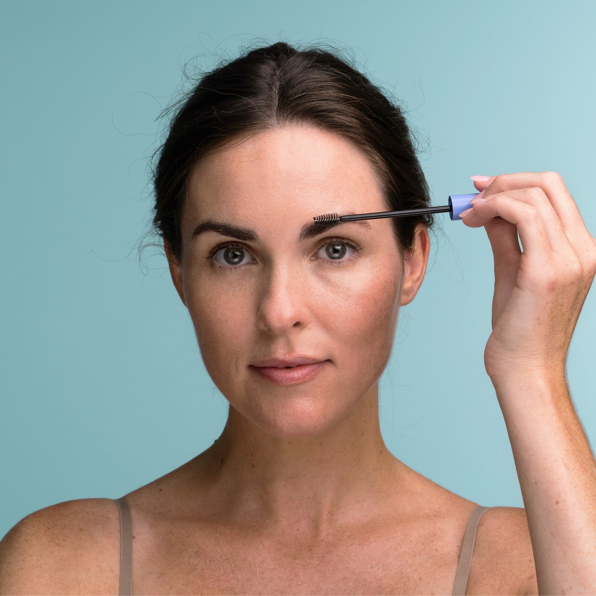 A woman applying the Obagi Eyebrow Boosting Serum using the applicator brush