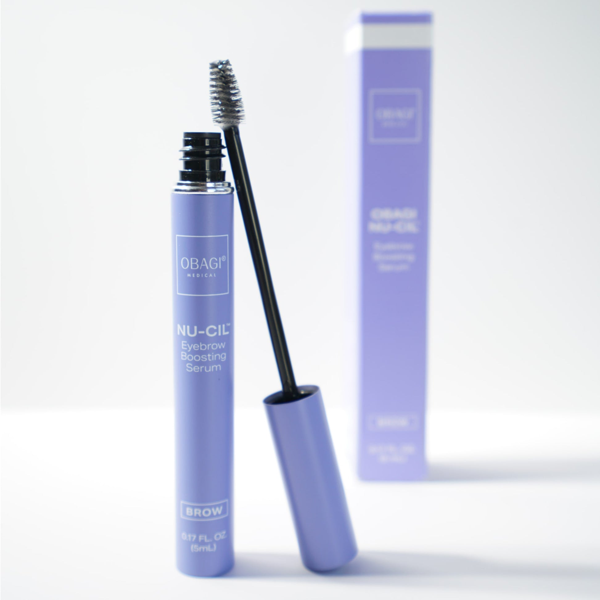 Obagi Eyebrow Boosting Serum open with the applicator brush leaning against it and box packaging in the background