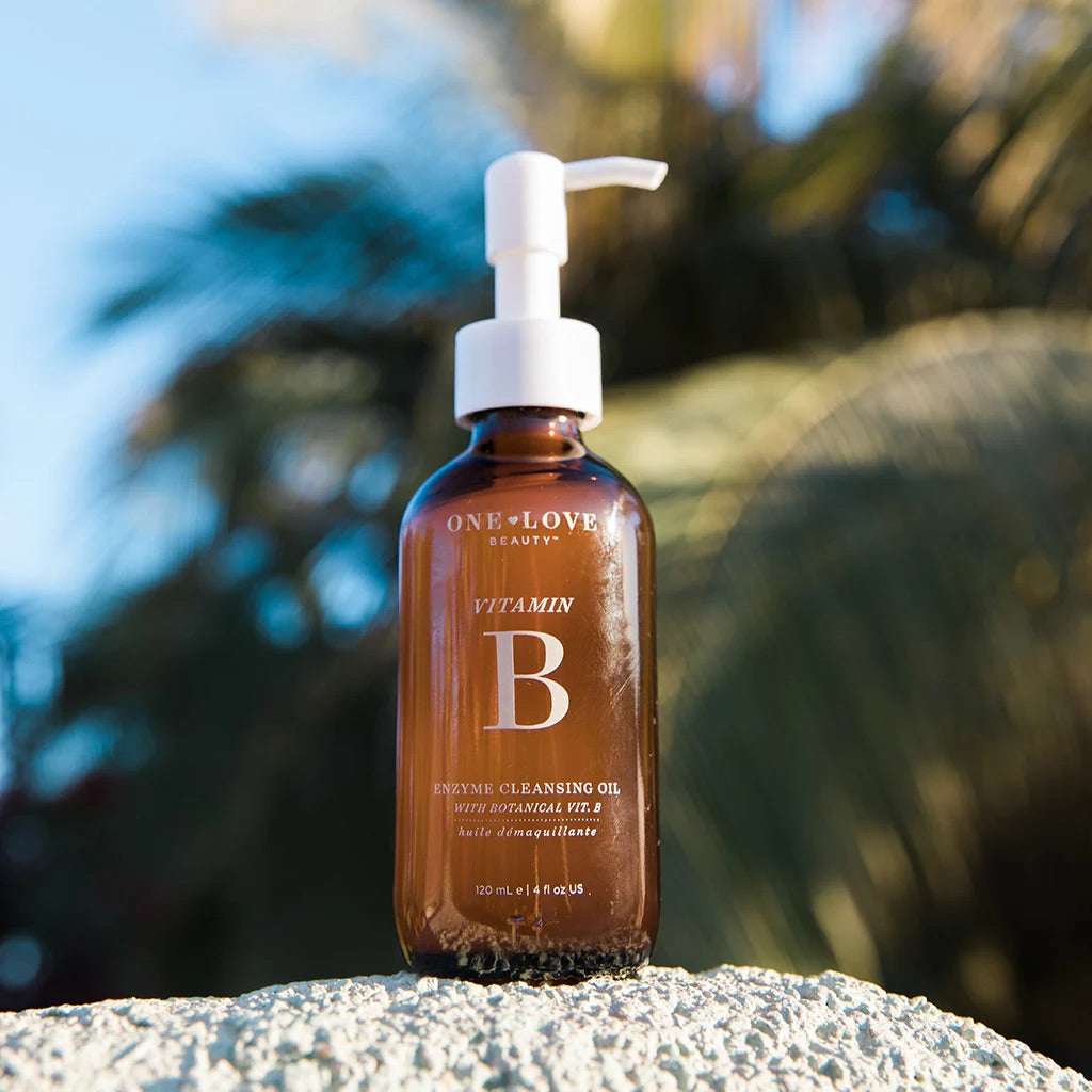One Love Organic Cleansing Oil bottle on a beach