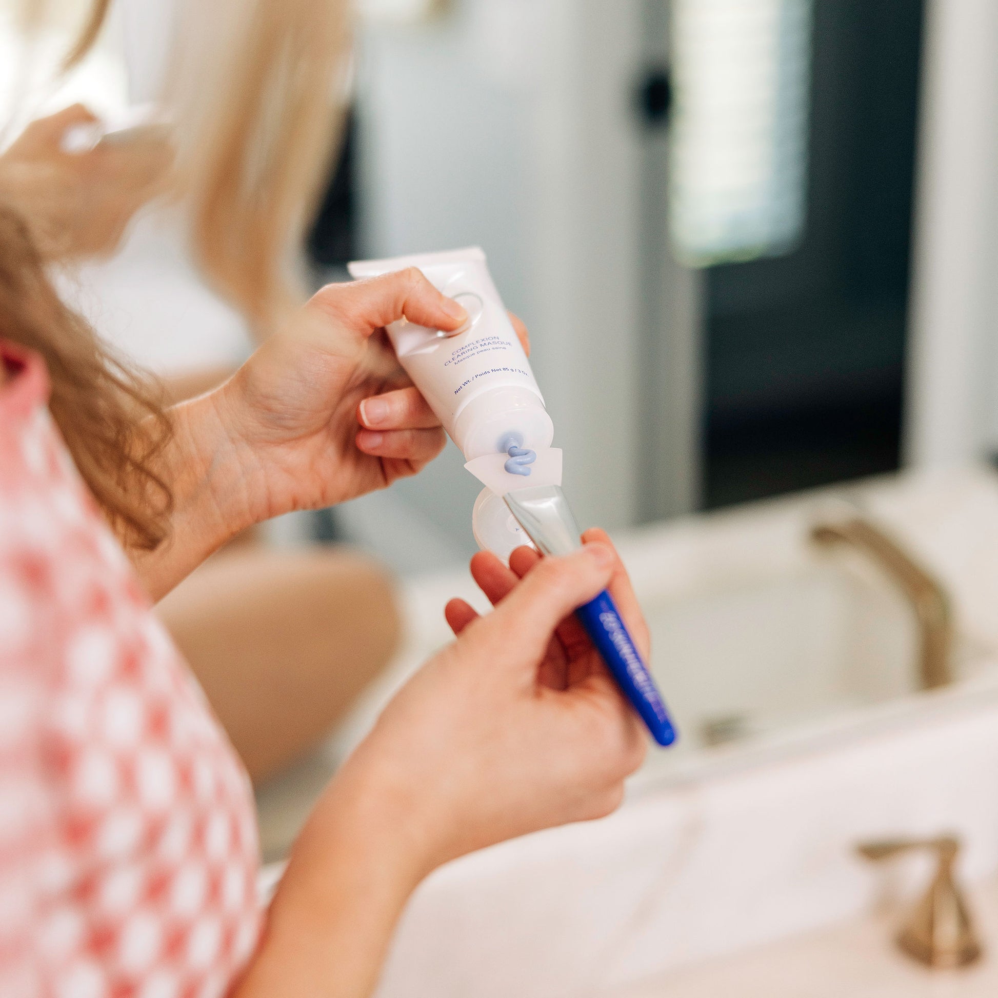 A woman applying the ZO Skin Health Complexion Clearing Masque to a brush