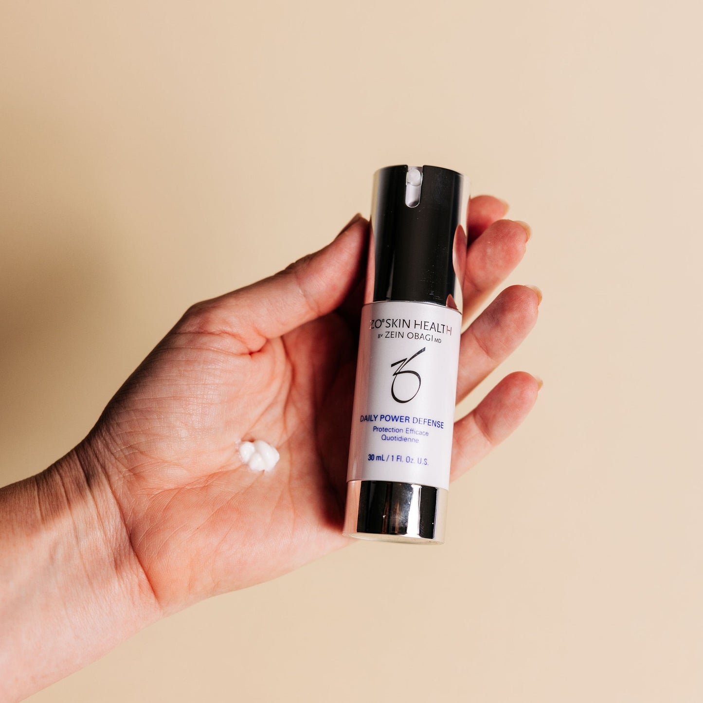 A hand holding Daily Power Defense Serum in travel size from ZO Skin Health