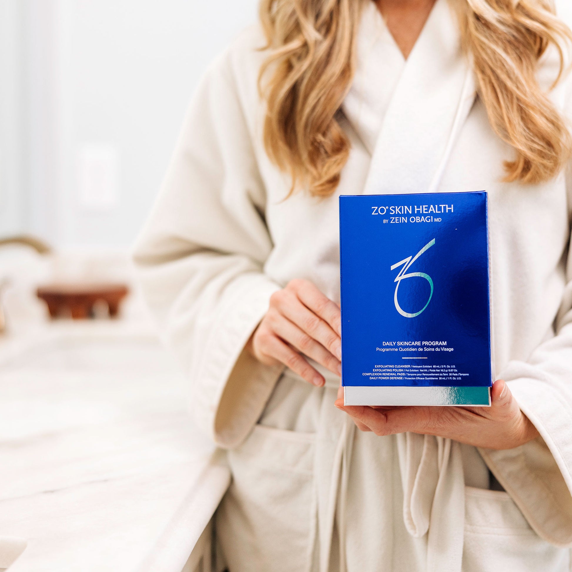 A woman holding the packaging for the Daily Skincare Program from ZO Skin Health