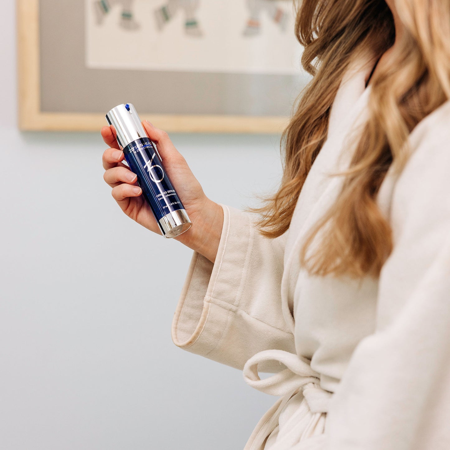 A woman in her robe using the ZO Skin Health Firming Serum