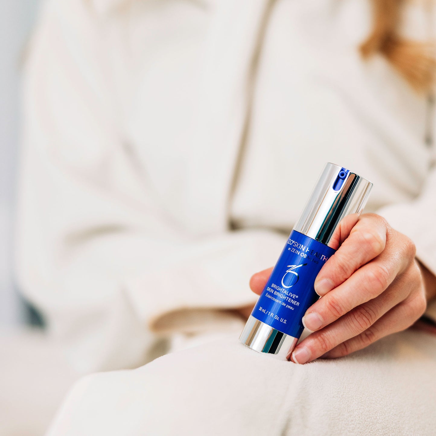 A woman holding ZO Skin Health's Brightalive Skin Brightener