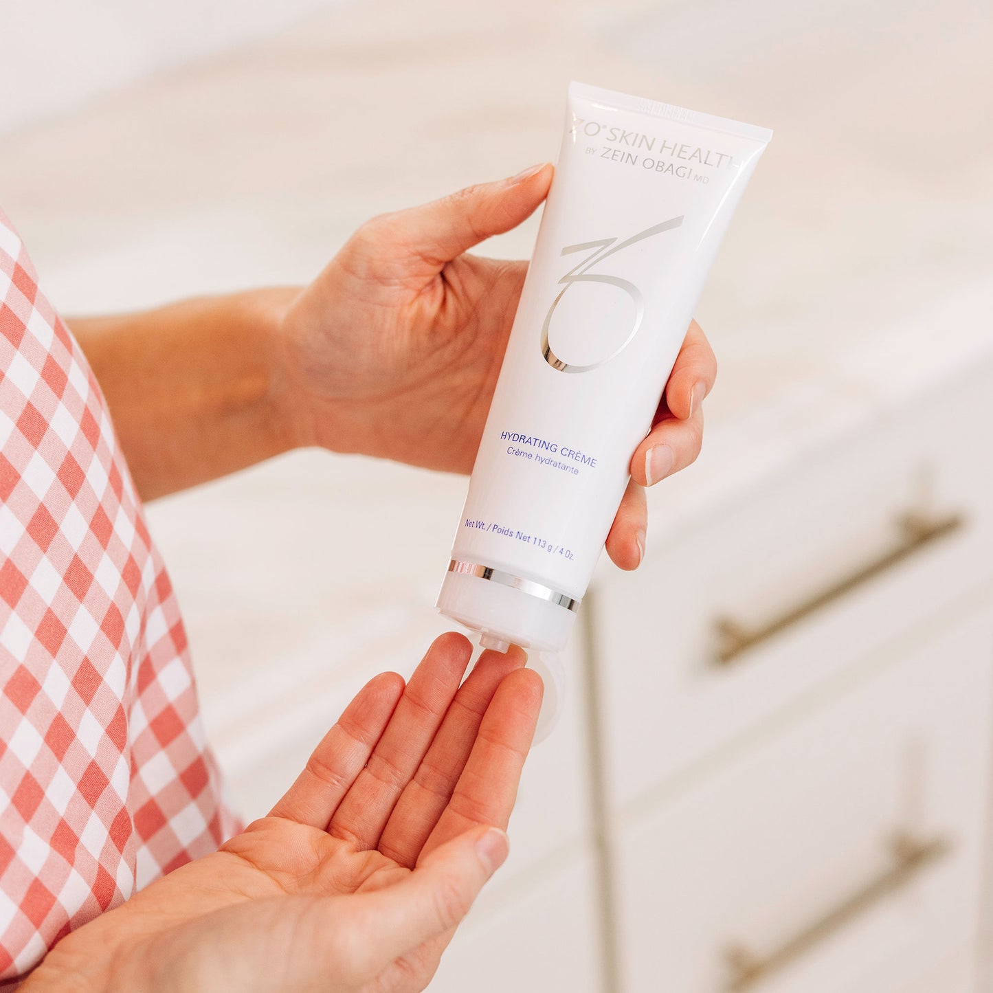 A woman applying the ZO Skin Health Hydrating Creme to her fingertips