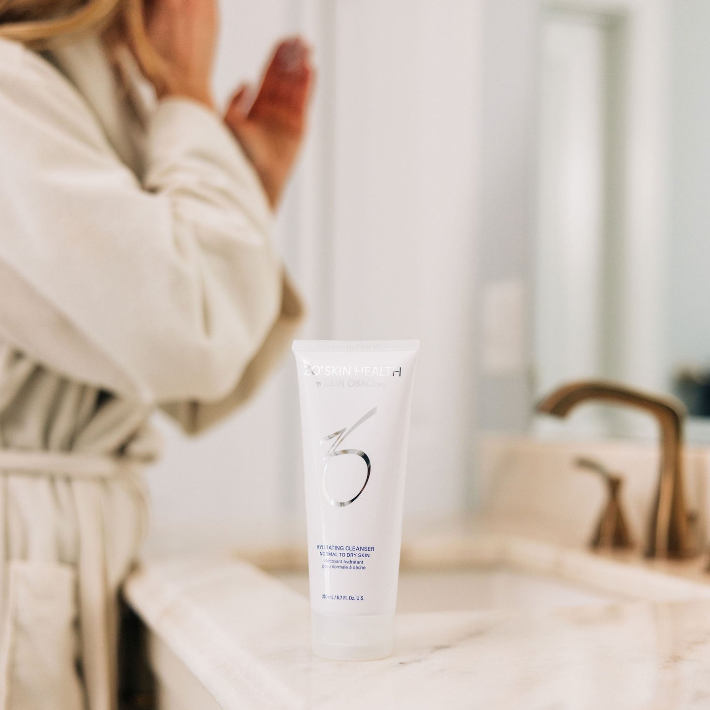 A woman applying her ZO Skin Health Exfoliating Cleanser in her bathroom
