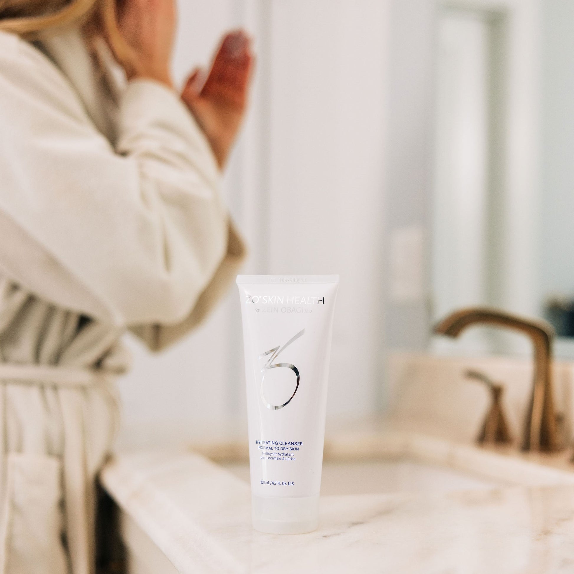 A woman applying her ZO Skin Health Exfoliating Cleanser in her bathroom