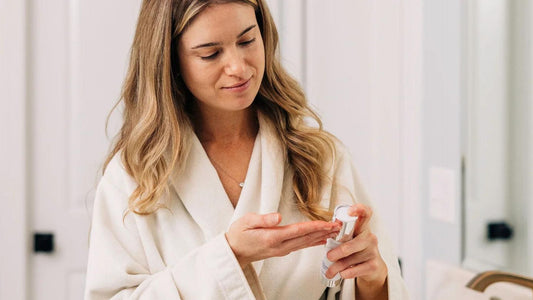 A woman applying ZO Skin Health Daily Power Defense in her bathroom