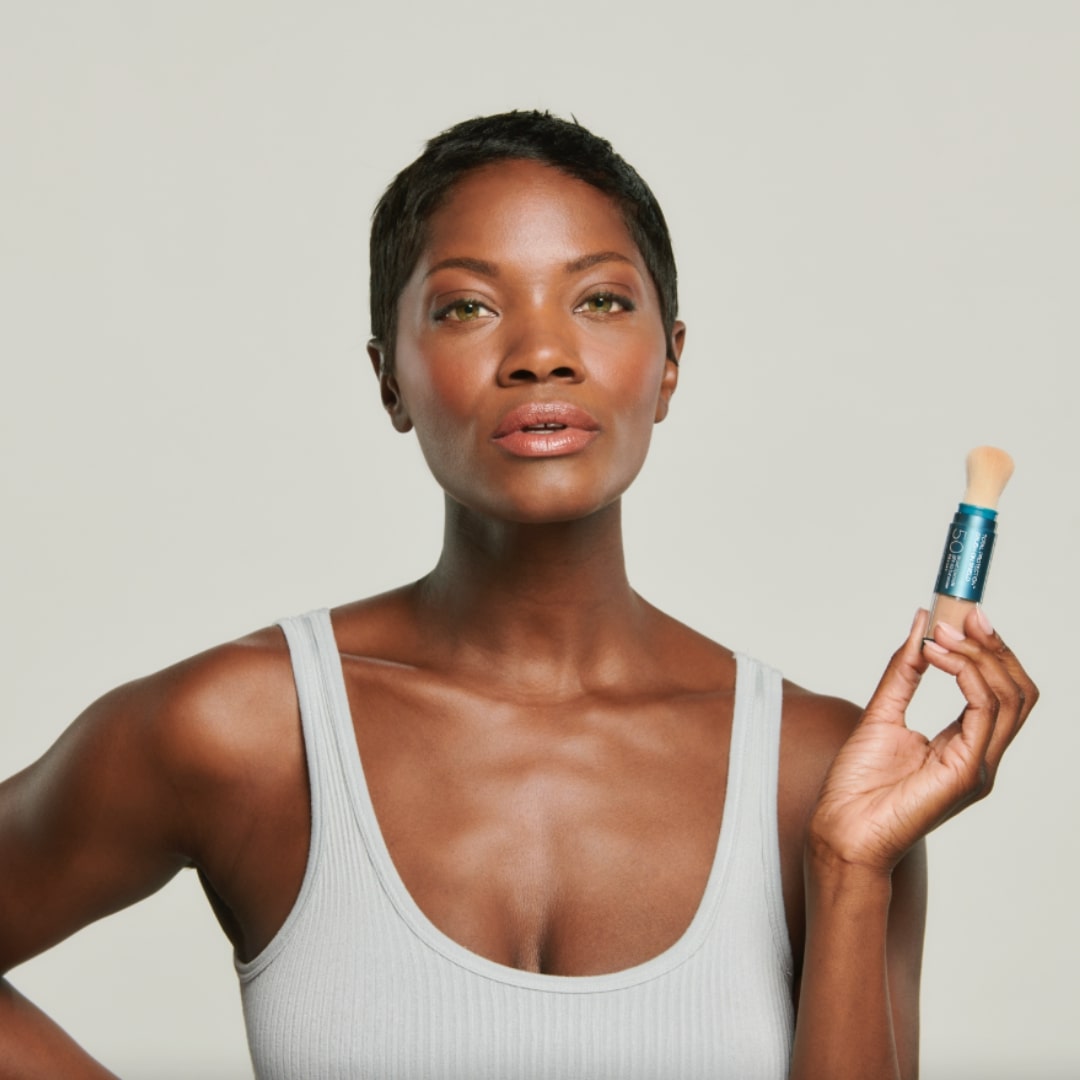 Woman showing the Colorescience Brush-On Shield Sunscreen