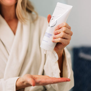 A woman in her bathroom using ZO Skin Health Hydrating Cleanser